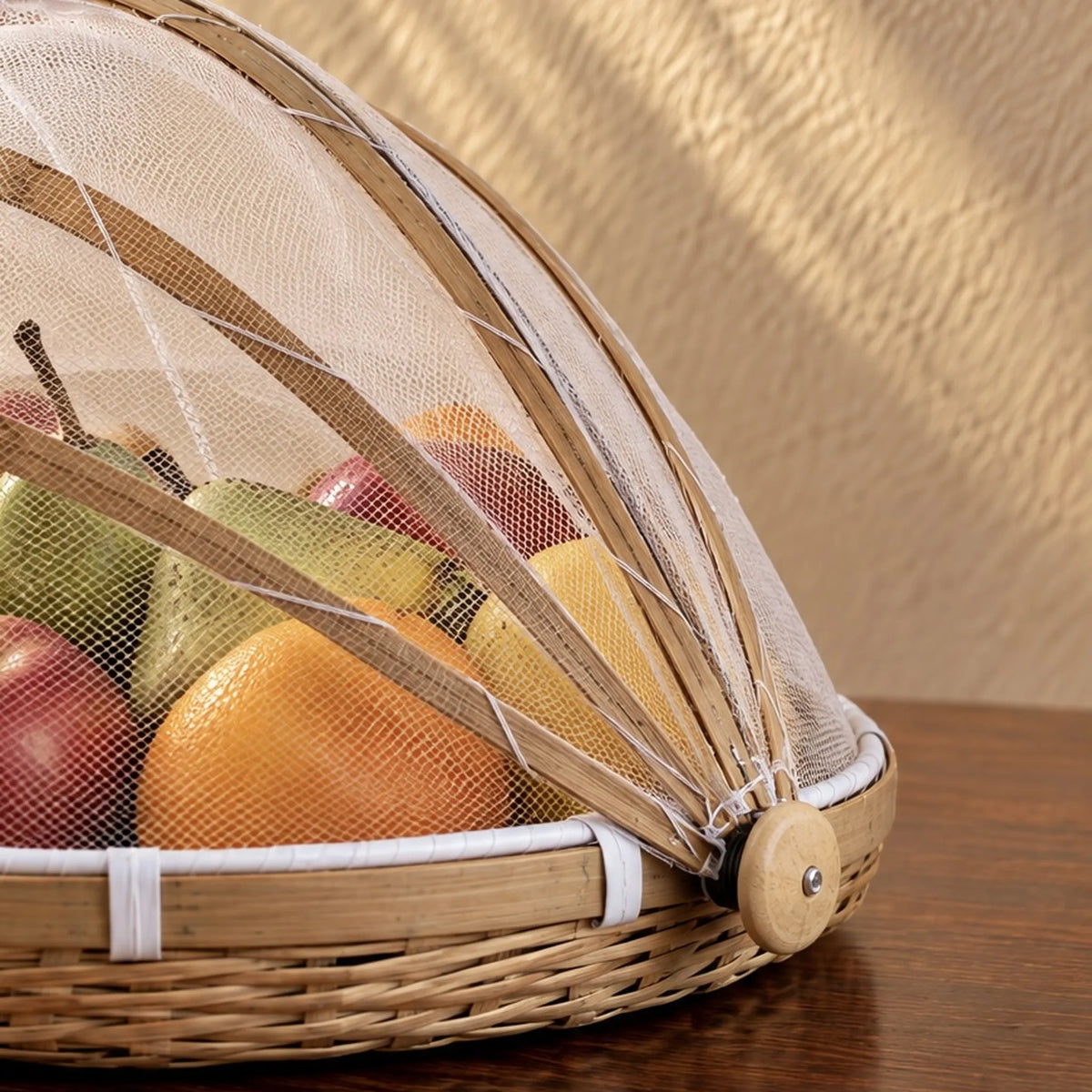 Cloche alimentaire en bambou fermée sur un assortiment de fruits frais